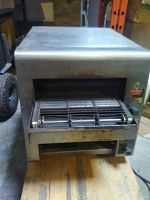 Front view of commercial toaster with conveyor belt inside showing the toasting mechanism and metal casing.