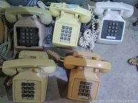Top view of 5 vintage DTMF push-button corded telephones in various colors arranged on floor