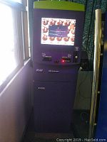 Photo of a black industrial kiosk with green top edge, featuring a touchscreen displaying a Windows error screen, card dispenser, receipt printer, bill accepter, and card reader slots below the screen.