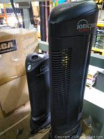 Two black Ionic Pro air purifiers positioned on a surface, one Ionic Pro Turbo model is larger and taller, other smaller, with visible front grilles and control buttons.