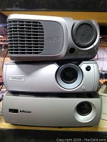 Photo showing a stack of three projectors: an Acer projector on top and two InFocus projectors below.