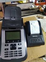 Tellermate TX3500 banknote counter with keypad, display, and banknote slot visible, sitting on a cardboard surface.