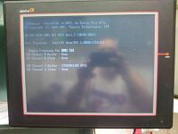 Front view of the touchscreen industrial computer showing the BIOS splash screen labeled Omni Alpha and Intel Atom CPU info.