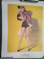 Photo of the pin-up print titled Marilyn The Spanish Girl by Earl Moran showing a woman posed with a mask, wearing black shorts and a pink shawl, on yellow background with signature and number.