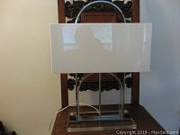 Front view of lamp showing white rectangular shade, chrome arch, Lucite base, metal supports