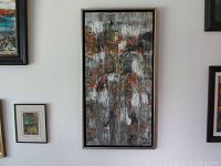 Full view of framed abstract painting hung on wall alongside other artworks