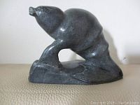 Front side view of dark gray soapstone seal sculpture showing detailed facial features and smooth carved body.