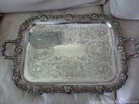 Top view of large rectangular silver plated serving tray showing ornate floral etching and decorative raised border with grape clusters and leaves.