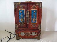 Front view of closed cabinet showing two doors with blue enamel dragon panels, brass hardware and corner protectors.