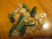 Photo showing 21 assorted semi-precious stone beads in green and clear shades on wooden surface.