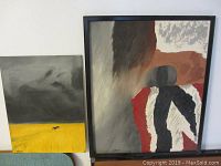 Photo showing two vintage oil paintings on board side by side, one framed and one unframed, placed against a wall on the floor.