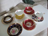 Six cups and saucers on white table from front angle