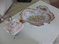 Photo showing both the vintage German porcelain bowl and Dresden figurine together on a white surface for scale and condition