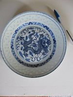 Top view of the porcelain plate showing blue dragon design in center with surrounding cloud motifs and textured border.