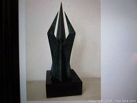 Front view of green patina bronze abstract sculpture on black marble base
