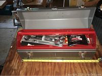 Wide view of silver Craftsman toolbox open with red tray, containing assorted sealed new tools including socket wrenches and sealed packs