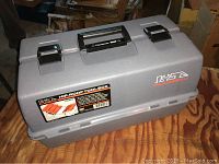 Closed gray plastic Hyde Hip Roof Tool Box with carrying handle and metal latches on wooden surface.