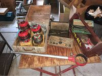 Set of large scale red metal pipe tap and die dies in metal case with wooden lid open and large pipe threader featuring a long handle and red head.
