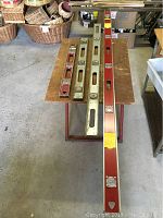 Four metal levels laid out on a wooden table in descending order by length.