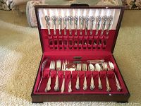 Full view of the Rogers Bros silver plated flatware set displayed in an open wooden box with red lining, showing multiple pieces organized inside.