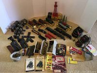 Overview of engines, freight cars, track, controllers, instruction manuals and accessories arranged on carpet