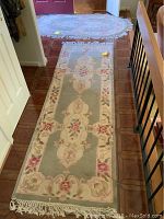 Full view of rectangular runner rug with oval rug in background near door, showing overall size and placement.