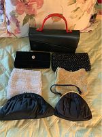 Seven vintage handbags and purses arranged on a bed, showing different materials and styles.