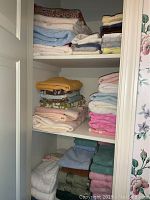 Closet shelf with stacks of various colored and sized towels including bath, hand, and washcloths.