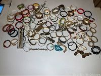 Wide view of assorted costume jewelry including multiple colorful bangles and metallic bracelets laid flat on a white surface