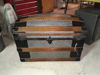 Front view showing metal panels with diamond plate texture, horizontal wood slats, black metal corner protectors, and latch closure.