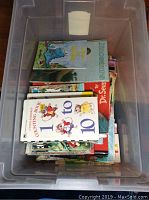 Photo of a plastic bin filled with various vintage children's books with colorful covers showing titles such as 'Dinosaurs,' 'Counting Book 1 to 10,' and 'Dr. Seuss'.