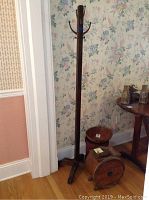 Wooden coat rack with hooks and base, seen with pantry box and churn nearby