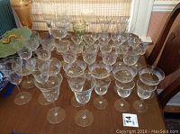 Front angle showing multiple rows of clear glass stemware with various patterns including etched and cut designs.