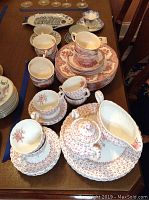 Overall view of Johnson Bros Rose Bouquet china with stacked plates, teacups, saucers, bowls, and fish-shaped plate on dining table.