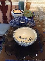 Photo showing various serving bowls including a large 20-inch smokey glass ruffled serving dish, blue and white ironstone bowl, nested ceramic mixing bowls, and assorted vases.