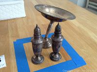 Set of two tarnished sterling silver salt and pepper shakers with a weighted tilted sterling silver cup.