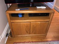 Front view of oak TV stand with electronics on open shelf and double-door cabinet below.
