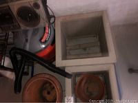 Image showing 2 painted wooden plant stands/containers, beige color, one large square, one smaller square, with a wet-dry vacuum and Panasonic cassette player radio stacked on top, all placed on basement floor near a wall.