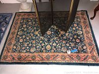 Large floral area rug blue background with orange and pink border, under brass fireplace screen panels