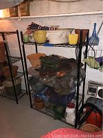 Two black metal shelves holding various garden related items and decorative pots. Shelves are sized 35.5"x14"x54". Items visible include plant containers, tarps, American flags, garden chemicals, and bird figurines.