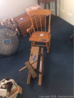 Child wooden rocking chair and vintage wooden hobby horse positioned on carpeted floor alongside fan and other furniture.