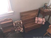 Cedar trunk open showing interior and broken hinges, alongside the miniature wingback chair and decorative box beside a wooden end table.