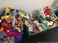 Large assortment of colorful Ty Beanie Babies plush toys and McDonald's promotional plush in plastic bins and on a blue surface