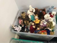 Photo of a large plastic container filled with assorted TY Collectible stuffed toys including teddy bears, a Curious George doll, and other plush characters.