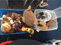 Blue plastic bin with Disney stuffed animals, including a large Tigger, a brown bear, and a large plush deer or moose, next to two bins with vintage wooden toy blocks and toy wooden houses.