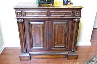 Front view of Hooker wooden cabinet showing two drawers and two doors, with decorative column accents and surface scratches