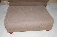 Top-down view of beige woven fabric ottoman with rounded wooden feet, showing overall condition.