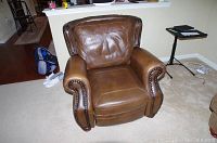 Front view of brown leather recliner showing overall shape, cushioning and wear spots.