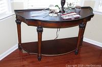 Front view of dark wood side table against corner walls with decorative items on top shelf