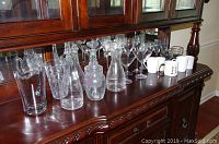 Front view showing entire assortment of glassware and mugs on wooden buffet top